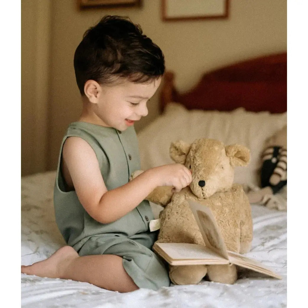 child in arthur romper on bed with stuffed toy